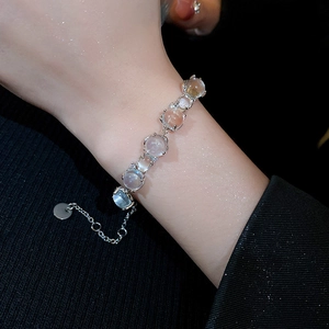 Detailed close-up of a silver heart bracelet with blue faux cat-eye stones on wrist