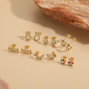 Ensemble de boucles d'oreilles fleurs plaqué or 14K avec zircons colorés sur fond beige