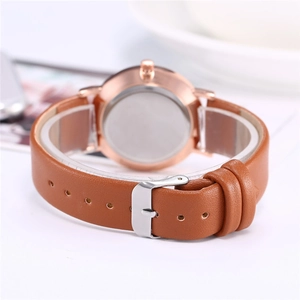 Detail view of the rose gold watch case and brown leather strap with silver buckle