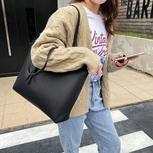 Large black lychee pattern leather tote bag shown on model in a stylish street style view