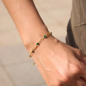 Close-up of golden stainless steel bracelet with green zircon stones on a woman's wrist