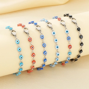 Detail of five evil eye bracelets in various colors draped over a beige fabric display roll