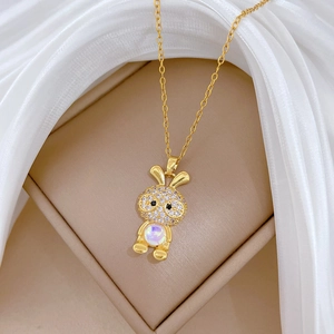 Macro shot of gold rabbit pendant with glittering zircons and cat eye stone on silk