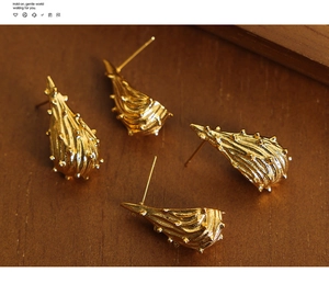 Detail van gouden druppeloorbellen met stippeltextuur op een donker houten oppervlak