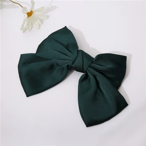 Detailed view of an elegant dark green satin bow hair clip on a clean white background