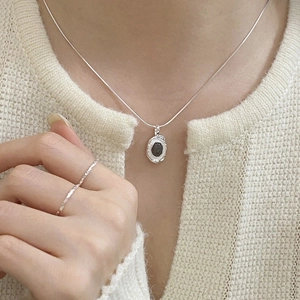 Detail view of a silver necklace with black onyx pendant and a matching textured ring