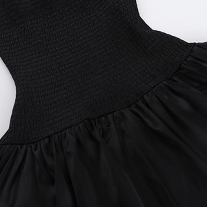 Detail of black dress featuring elastic smocked waist and soft pleated fabric textures