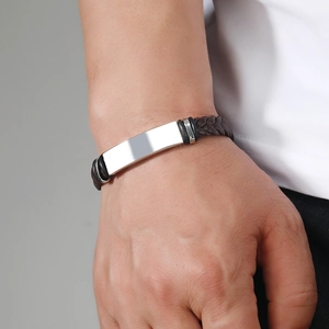 Close-up of men's braided dark brown leather bracelet with a polished silver metal plate