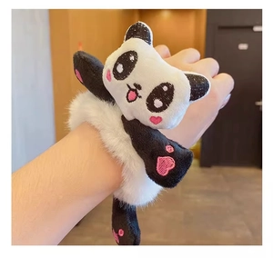 Détail d'un chouchou panda en peluche avec broderie porté comme bracelet au poignet
