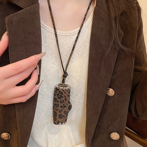 Close-up of leopard print mini bag pendant with white hand-stitched edges and metal snap