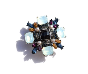 Detail of vintage star brooch with square black stone, white pearls and colored gems
