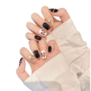 Handmade ballerina press-on nails in black and white cow print with gold foil accents