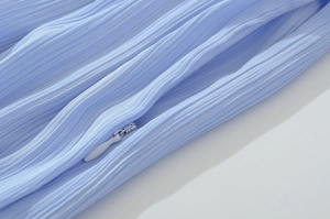 Gros plan sur la texture du tissu plissé bleu clair avec détail de fermeture éclair invisible
