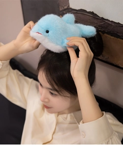 Gros plan d'une pince à cheveux dauphin en peluche bleue sur la tête du mannequin