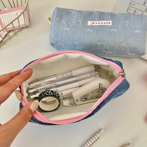 Detail view of denim stationery pouch with bow embroidery and spacious inner compartment