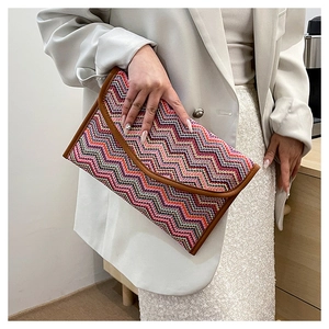 Detail of colorful chevron woven envelope clutch held by model for scale and style