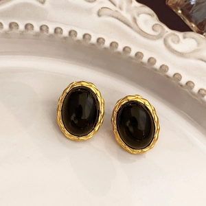 Macro shot of gold vintage flower earrings with black stone on a white ceramic tray