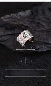 Macro shot of wide silver ring featuring intricate vine carvings and round moonstone