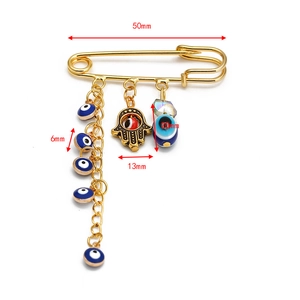 Detail of Hamsa hand and blue evil eye charms on a 50mm gold safety pin brooch