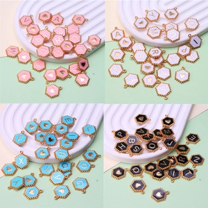 Macro detail of hexagonal colorful enamel alphabet pendants with gold-plated alloy frames
