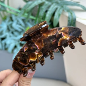 Dettaglio molletta per capelli in acetato tartarugato con riflessi viola e dorati cangianti