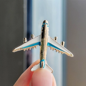 Close-up of a blue and white enamel airplane brooch held to show its realistic metal details