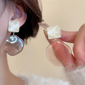 Detail showing elegant resin irregular earrings with iridescent finish on model ear
