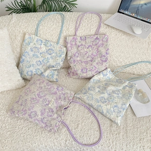 Detail of floral lace embroidery on canvas tote bags with elegant rope handles