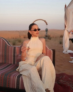 Detail of pleated beige halter top and wide-leg trousers set in a sunset desert landscape