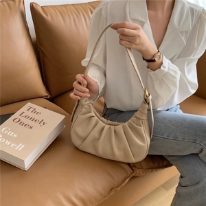 Fashionable beige pleated dumpling bag worn by a model in a cozy lifestyle setting