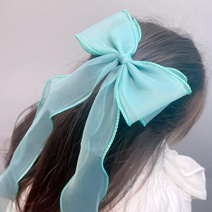Detail of mint green layered sheer ribbon bow hair clip on model with long hair