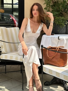 Detail of elegant white satin slip dress with deep V-neck and delicate lace patchwork