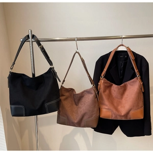 Three large matte hobo bags in black, dark brown, and caramel with white contrast stitching