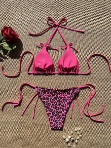 Close-up of rose pink and leopard print bikini set on a textured woven mat