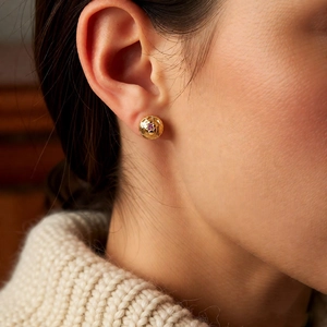 Detail of vintage 18k gold plated round wrinkled stud earring with purple gemstone on model