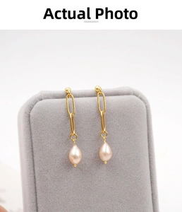 Detail of vintage 18K gold chain earrings with teardrop pearls on a velvet stand