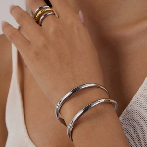 Minimalistisches Edelstahl-Armreif-Set mit geschichteten Ringen an Frauenhand