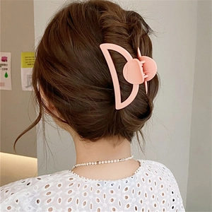 Pinza para el pelo de flor rosa mate sujetando un elegante peinado en pelo castaño