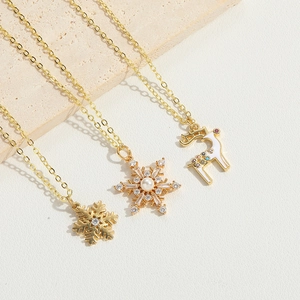 Detailed view of gold snowflake and reindeer necklaces on a beige stone block