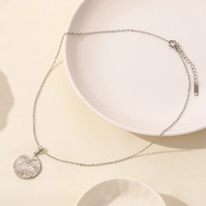 Detailed macro view of celestial star and moon engraved pendant on silver link chain