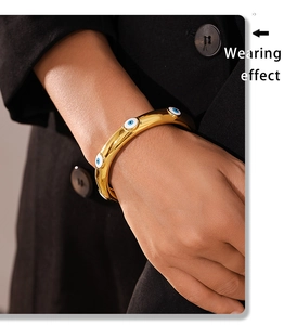 Wearing effect of golden titanium steel bangle with blue evil eye charms on wrist