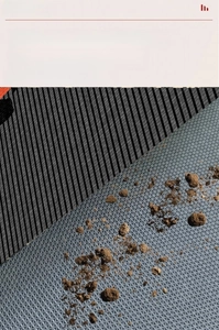 Detail of gray non-slip entryway mat with grid texture and dot plastic backing for cleaning