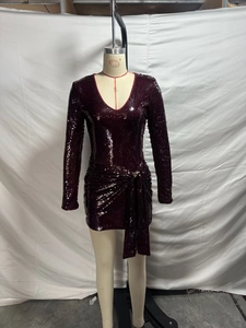 Dettaglio di paillettes e nodo scollo a V su un abito bordeaux a maniche lunghe