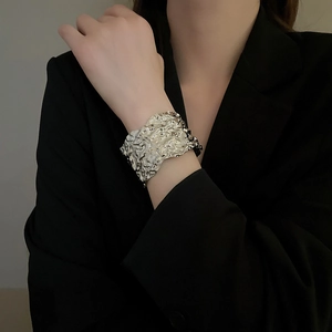 Macro detail of wide silver metal cuff bracelet featuring a unique wrinkled texture finish