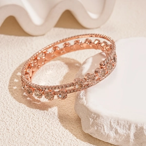 Macro detail of rose gold triple-layered zircon bracelet on a white textured stone