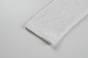 Gros plan de la couture double et de la texture en maille fine sur une manche blanche