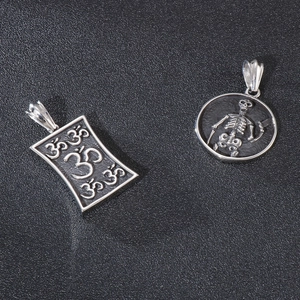 Vintage Edelstahl OM-Symbol und Totenkopf-Anhänger auf dunklem Hintergrund
