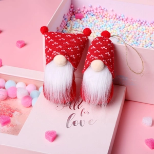 Close-up of two red and white knitted Christmas gnomes in a festive heart-themed gift box