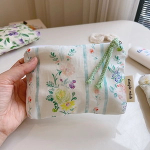 Detail view of cotton floral pouch with green stripes and woven zipper pull