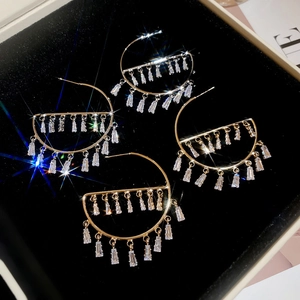 Detail view of gold hoop tassel earrings with cubic zirconia in a black velvet jewelry box